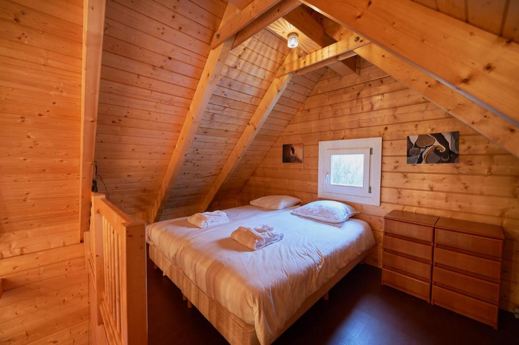 a bedroom with a bed in a wooden cabin at Harlingen Garden Apartment in Midlum