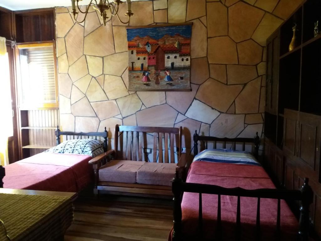Dos camas en una habitación con pared de piedra. en Cedro Departamentos Temporarios, en Posadas