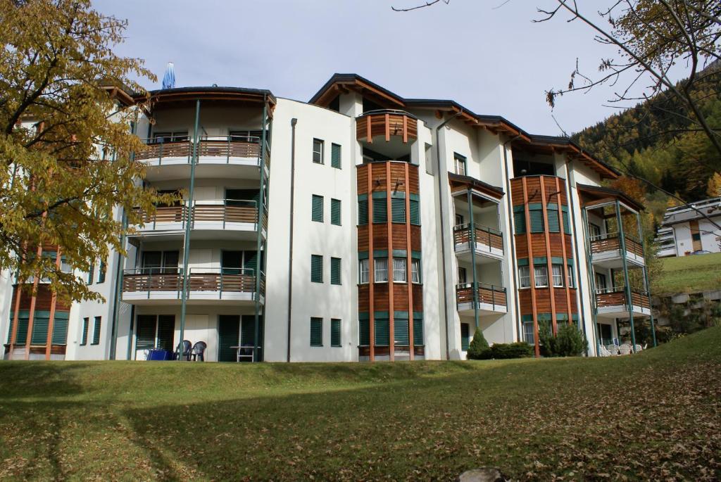 un gran edificio de apartamentos con balcones en una colina en Appartementhaus La Promenade en Leukerbad