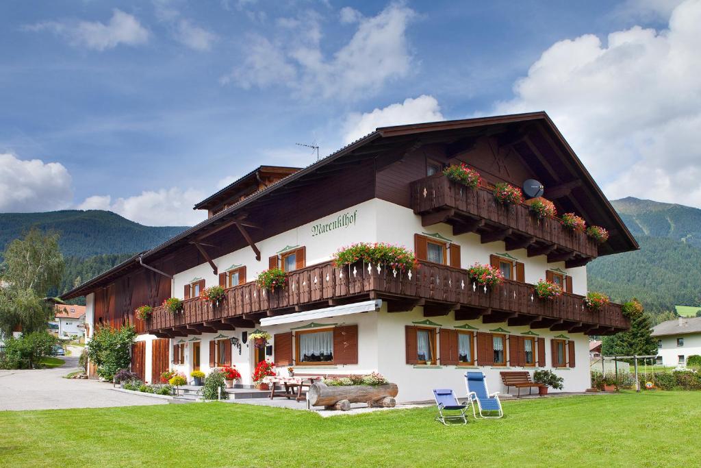 ein Gebäude mit einem Balkon und Stühlen im Gras in der Unterkunft Marenklhof in Welsberg-Taisten