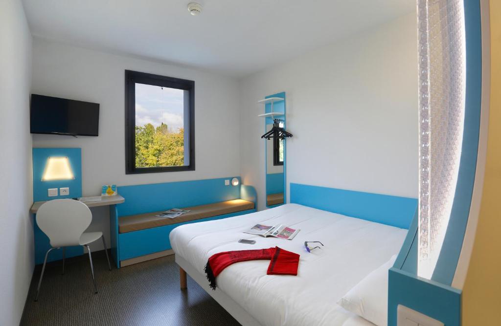 Cette chambre comprend un lit, un bureau et une fenêtre. dans l'établissement First Inn Hotel Blois, à Blois