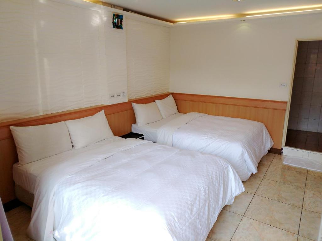 two beds in a room with white sheets at Hong Ben Hotel in Kenting