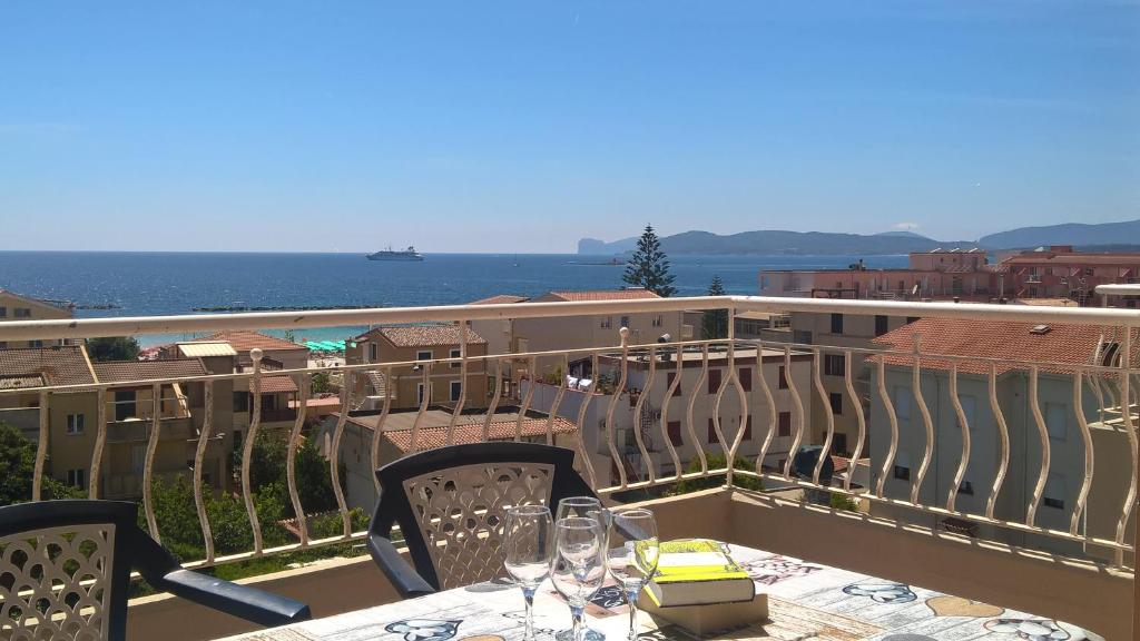 un balcón con una mesa con copas de vino. en Flat358, en Alghero