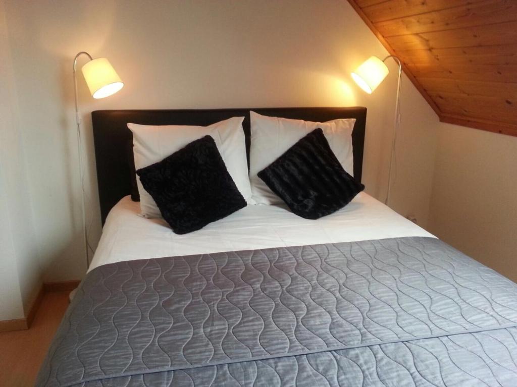 a bed with two black pillows on top of it at Khon Thai's House Brugge in Bruges