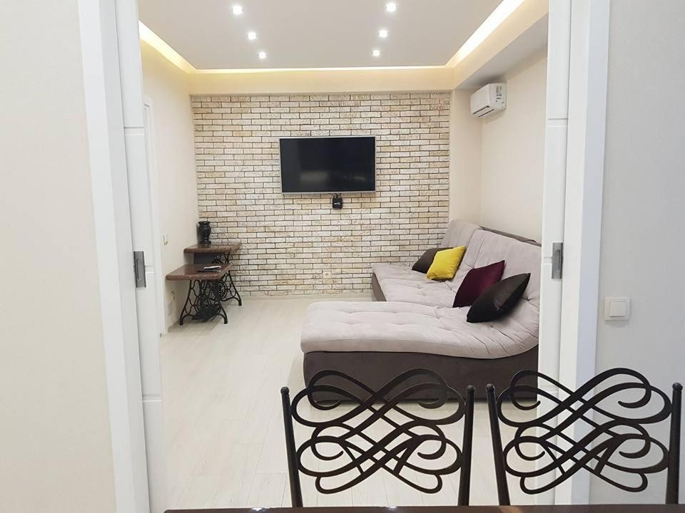 een woonkamer met een bank en een tv aan een bakstenen muur bij Royal Center-3 rooms 3 tv in Chişinău