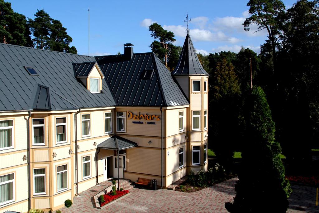 een groot wit gebouw met een zwart dak bij Dzintars Hotel in Jūrmala