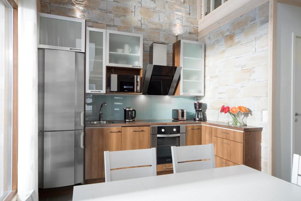 a kitchen with wooden cabinets and a stainless steel refrigerator at Holiday Club Himos Apartments in Jämsä