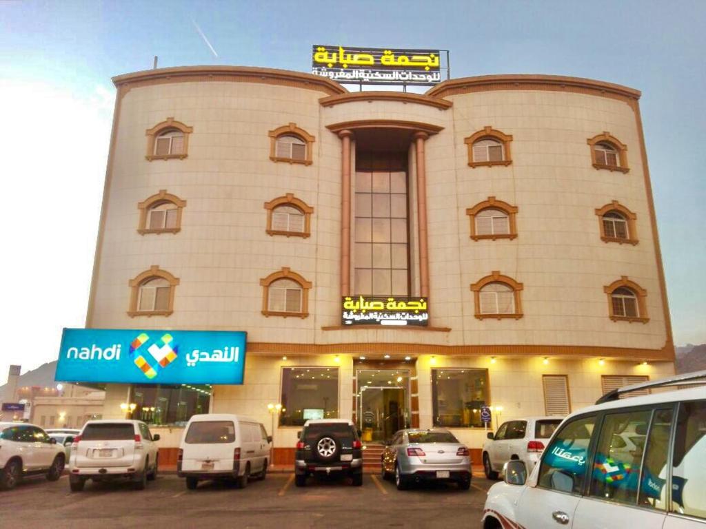 a large building with cars parked in a parking lot at Najmat Sabbabah Furnished Units in Hail