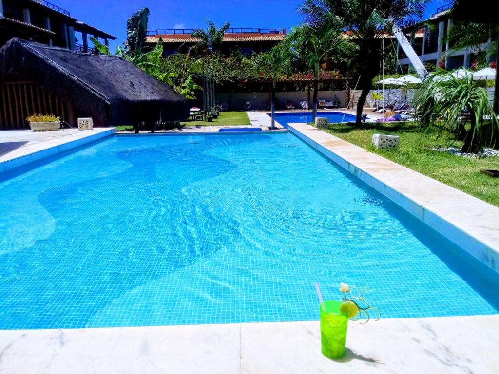 a large blue swimming pool with a drink in it at A7 Apt particular no condomínio Pipa Beleza in Pipa
