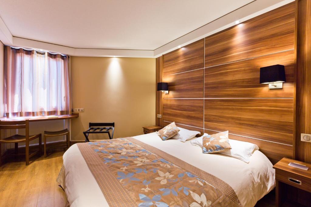 um quarto de hotel com uma cama com uma parede de madeira em Hotel Novel Restaurant La Mamma em Annecy