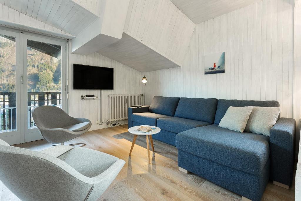 un salon avec un canapé bleu et une chaise dans l'établissement Residence du Brevent, à Chamonix-Mont-Blanc
