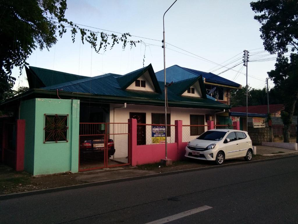 a white car parked in front of a colorful house at Moalboal Guesthouse in Moalboal