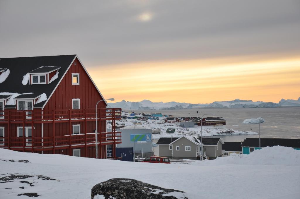 a red house in a small town in the snow at HOTEL SØMA Ilulissat in Ilulissat