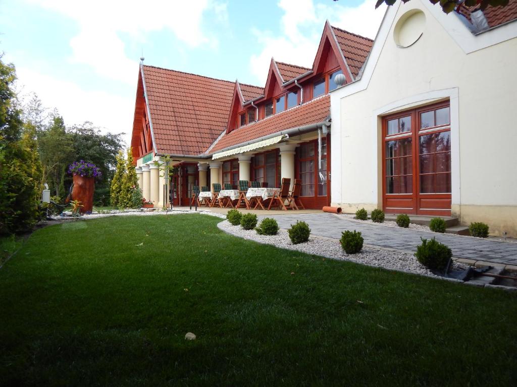 a house with a green lawn in front of it at Juniperus Park Hotel Kecskemét in Kecskemét