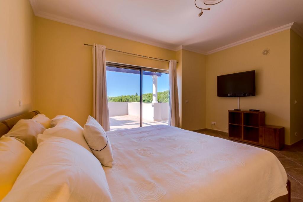 Schlafzimmer mit einem großen weißen Bett und einer Glasschiebetür in der Unterkunft Casa da Praia Verde in Praia Verde