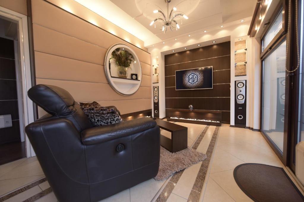 sala de estar con sofá de cuero y TV en H & V Residence - Bungalow Apartment, en Arad