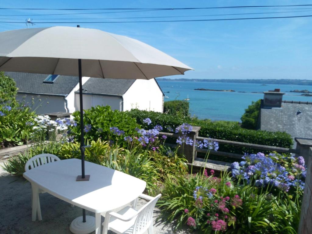 a white table with an umbrella and some flowers at Chez Tante Jeanne in Ploubazlanec