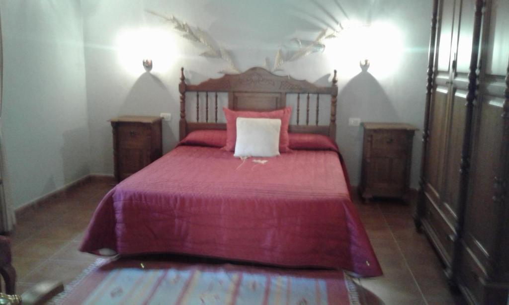 1 dormitorio con 1 cama con colcha roja en Casa Rural Rincón del Olivo, en Lomito Fragoso y Honduras