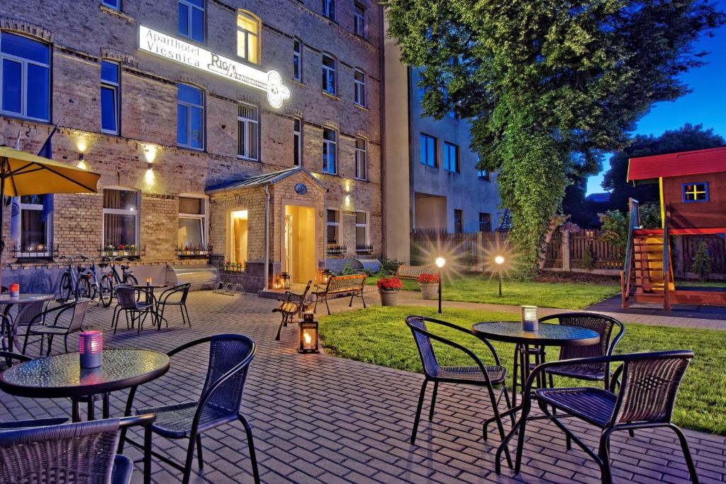 a patio with tables and chairs in front of a building at RIGAAPARTMENT SONADA Aparthotel - Private Parking & High Speed WIFI in Riga
