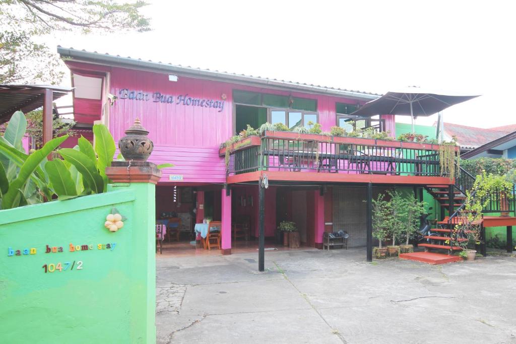 ein rosafarbenes Gebäude mit einem Balkon mit Pflanzen darauf in der Unterkunft Baan Bua Homestay in Chiang Rai