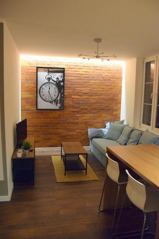 ein Wohnzimmer mit einem Sofa und einer Uhr an einer Ziegelmauer in der Unterkunft Apartament Marii Ludwiki in Koszalin