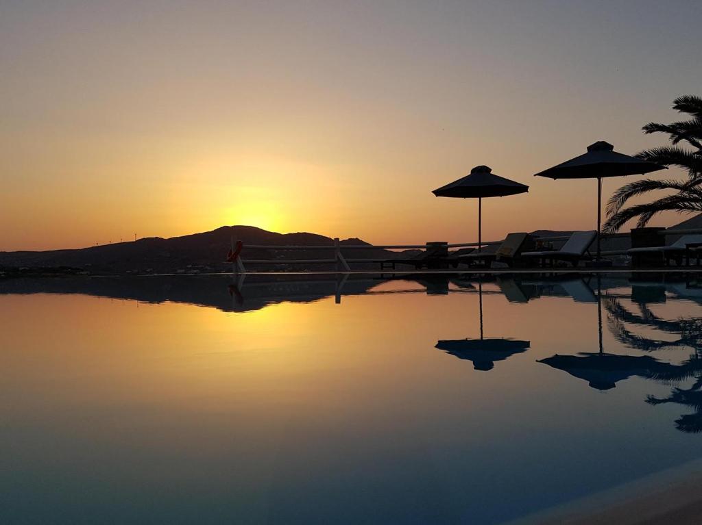a person walking by a pool with the sunset in the background at Maryo Village in Naousa