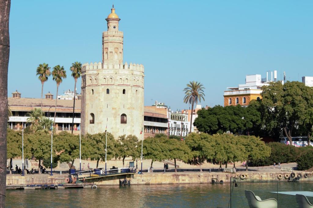 una torre de reloj junto a un cuerpo de agua en Triana Betis, en Sevilla