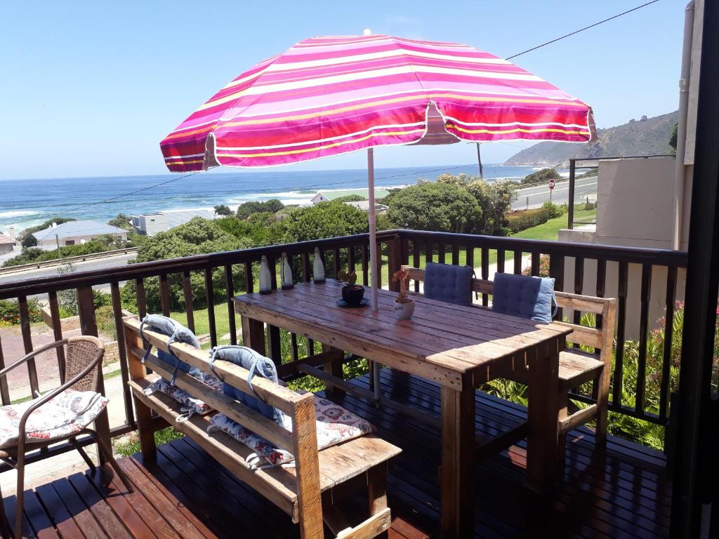 a wooden table with an umbrella on a balcony at Sea La Vie Beach House in Wilderness