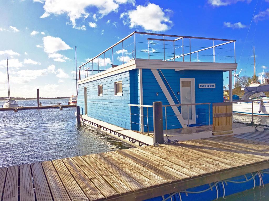 ein blaues Gebäude auf einer Anlegestelle am Wasser in der Unterkunft Ferienhaus auf dem Wasser - Hausboot Antje Frieda in Fehmarn