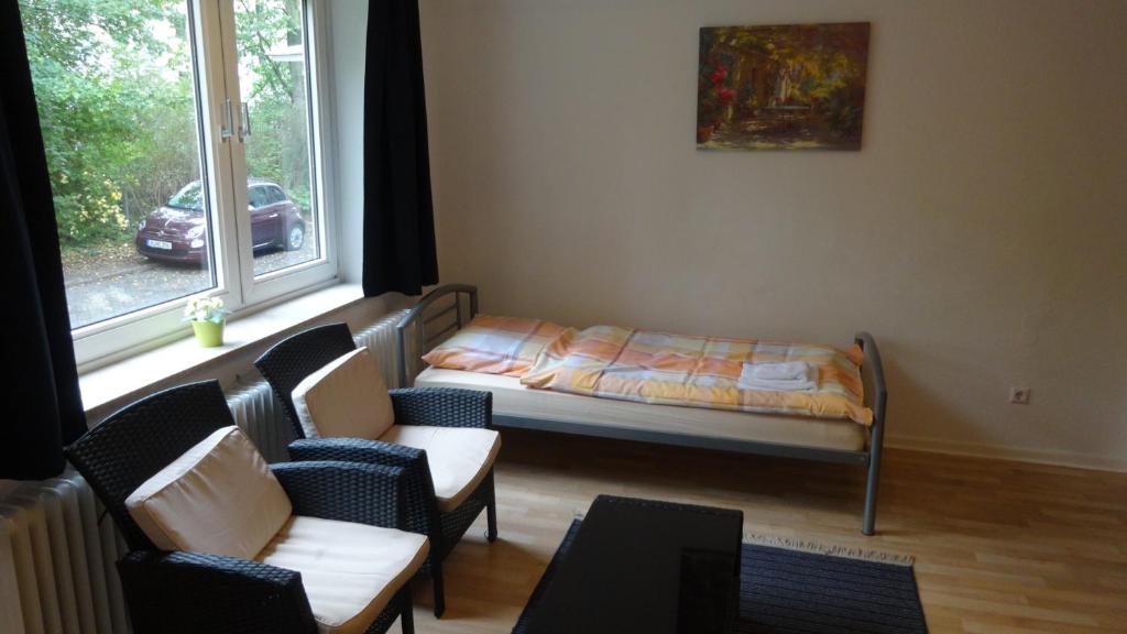 Zimmer mit einem Bett, Stühlen und einem Fenster in der Unterkunft Monteurzimmer - Messe Nord in Hannover