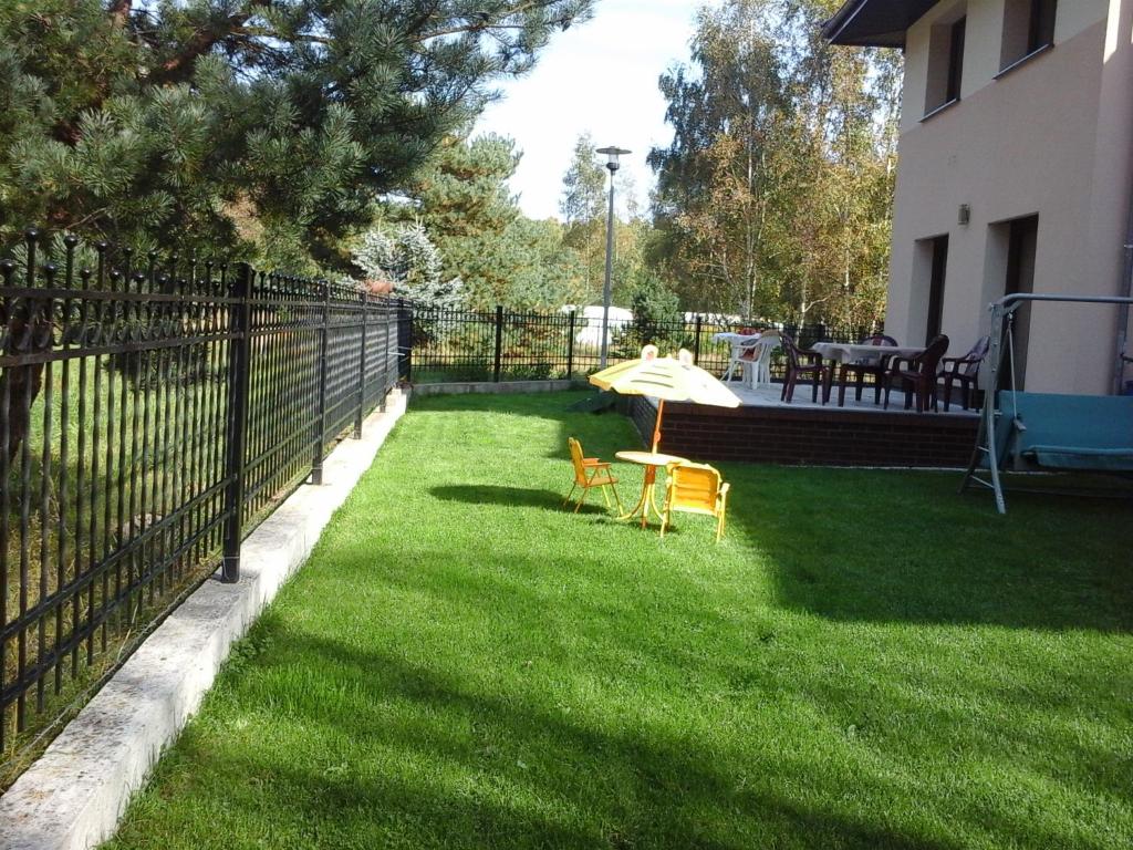 a patio with an umbrella and two chairs on the grass at Willa Olympia in Unieście