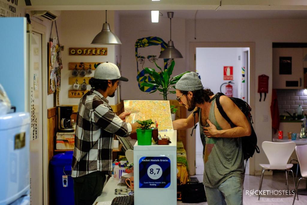 dos personas de pie en una tienda mirando un mapa en Rocket Hostels Gracia en Barcelona