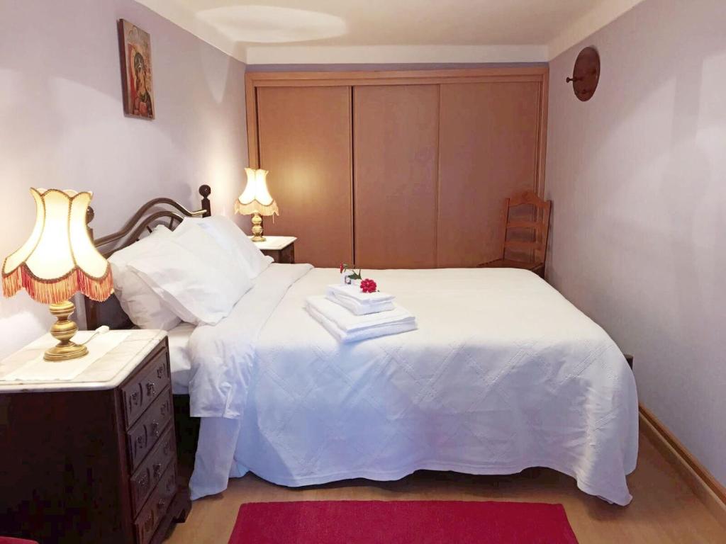 a bedroom with a white bed with two lamps at A Casa da Avó Leonor in Idanha-a-Nova