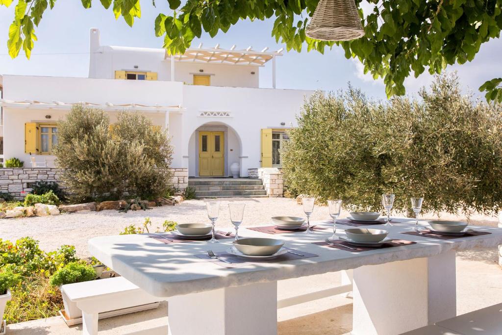 een witte tafel met kommen en glazen op een tuin bij Villa San Dimitrio House on the Beach in Logaras