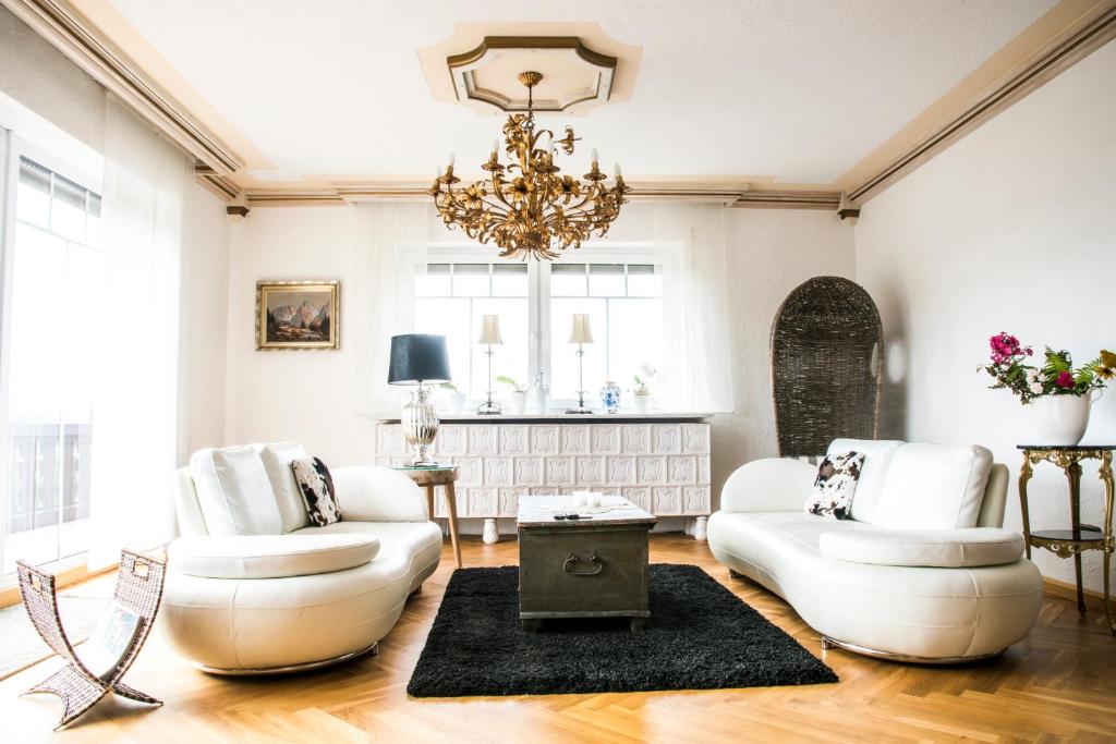 a living room with two white chairs and a chandelier at Friedrichsruh in Waldershof
