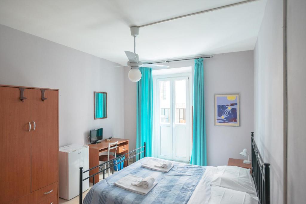 sypialnia z łóżkiem z niebieskimi zasłonami i oknem w obiekcie Gialel Guesthouse w Rzymie