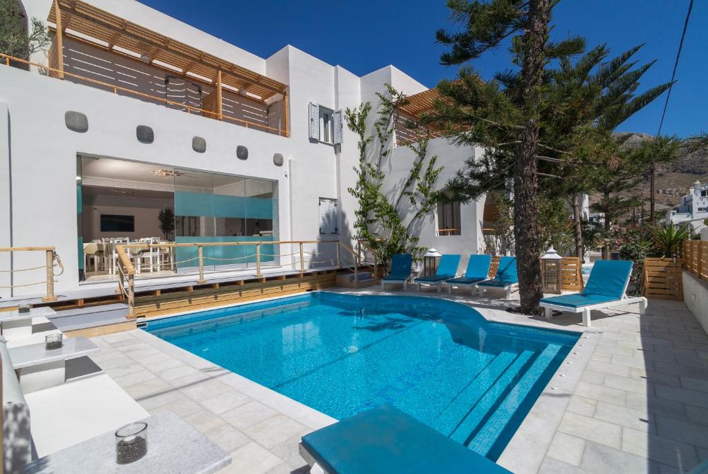 a swimming pool with blue chairs and a house at Amaryllis Hotel in Perissa