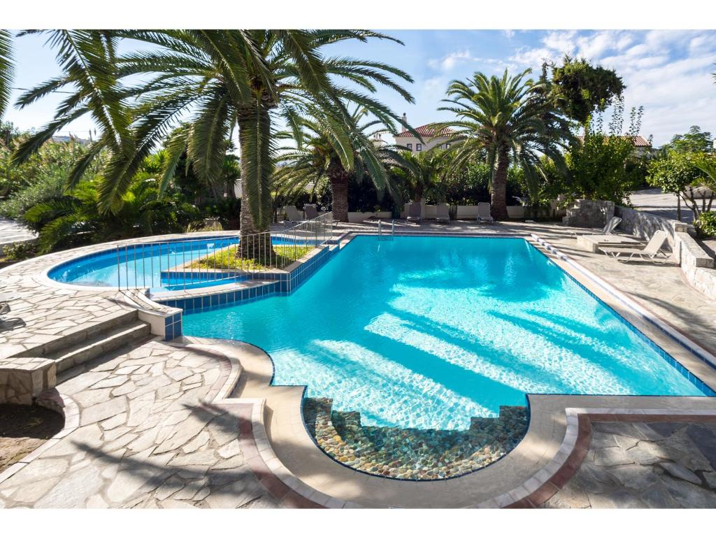 a swimming pool with a palm tree in the middle at Maria Suites in Plataniás