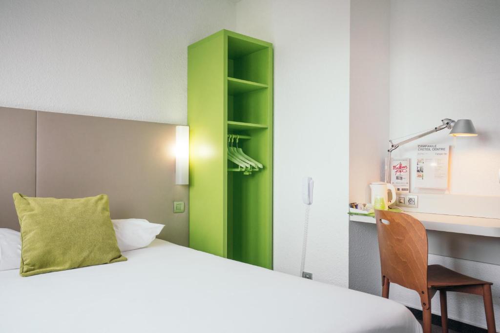 クレテイユにあるCampanile Créteil Centreのベッド、デスク、緑のキャビネットが備わる客室です。