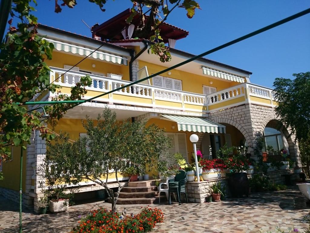 Casa amarilla con balcón en el patio en Apartmani Sonja, en Rab