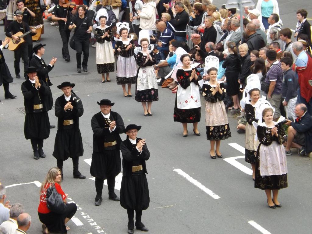 a group of people standing in the street in a parade at Hotel Du Port in Concarneau