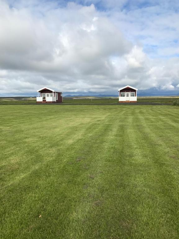 2 bâtiments blancs dans un vaste champ d'herbe dans l'établissement Hekla Adventures, à Hvolsvöllur