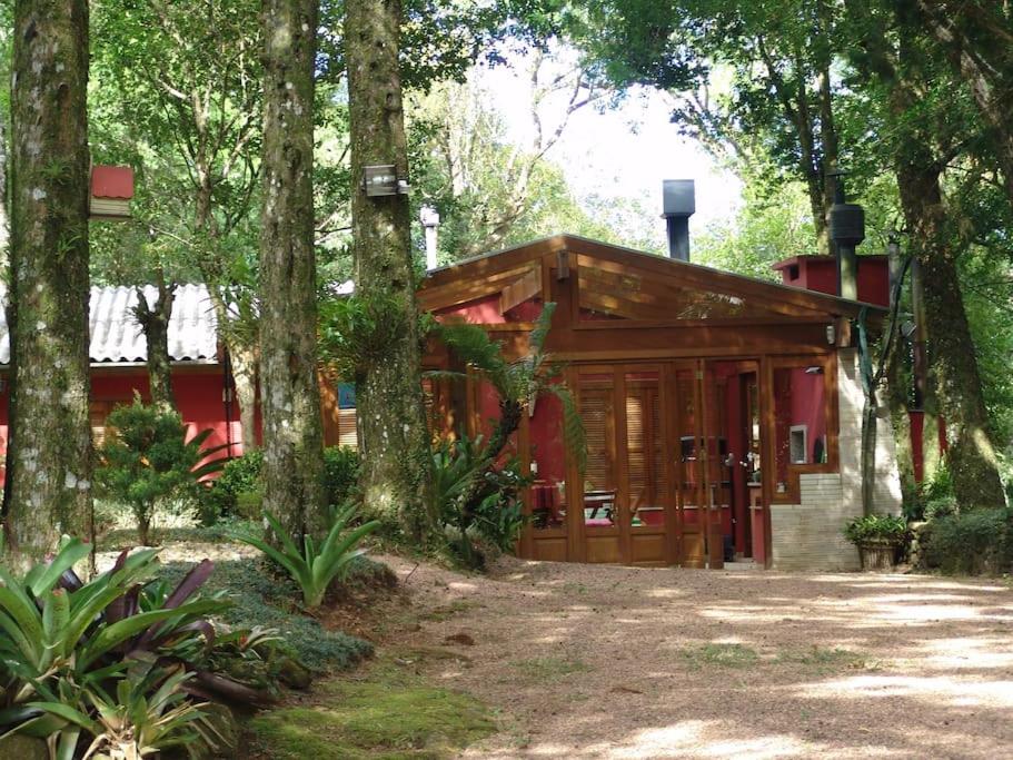 a red cabin in the woods with trees at Refúgio da natureza in São Francisco de Paula
