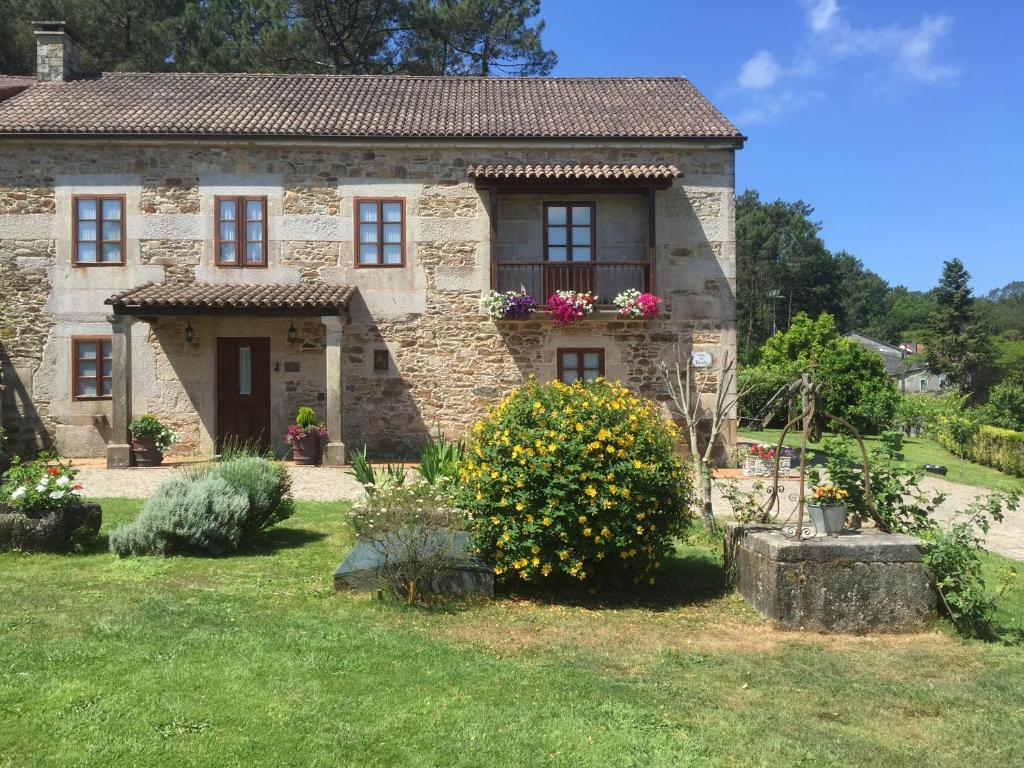 una vieja casa de piedra con flores en un patio en Casa Do Tarela, en Lousame