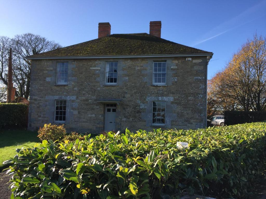 una vieja casa de piedra con un seto delante de ella en Church Farm, en Gillingham