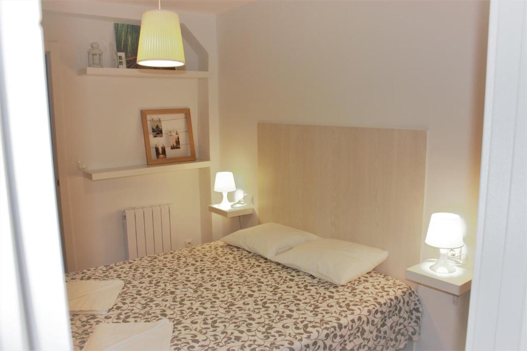 a small bedroom with a bed and two lamps at Vive Vitoria en Almendra Medieval C60 in Vitoria-Gasteiz