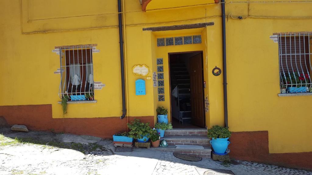 una casa amarilla con macetas delante de ella en B&B Partaitria, en Dorgali