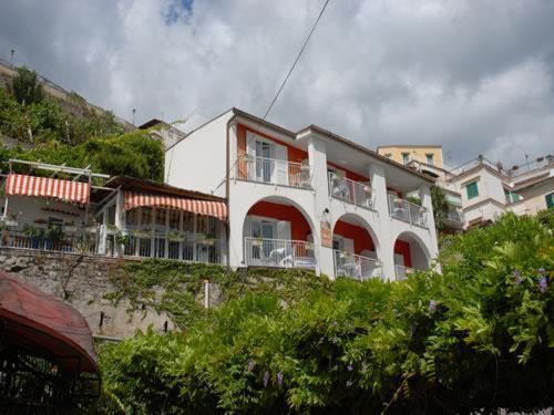 um edifício branco com portas e janelas vermelhas em Maison Raphael em Minori