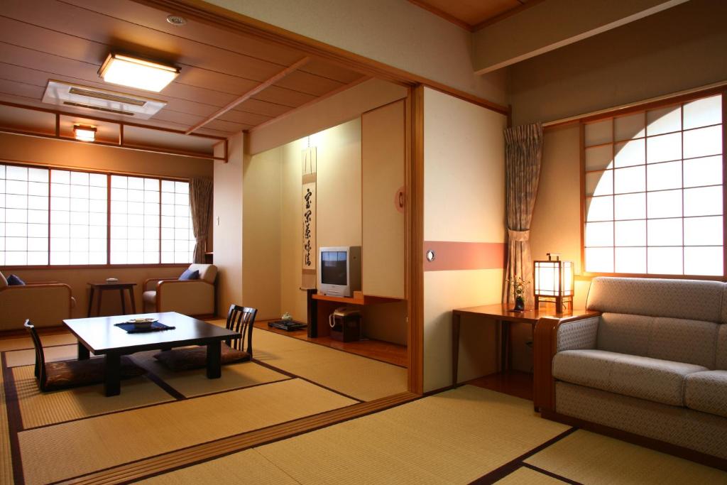 a living room with a table and a couch and a television at Takinoya Bekkan Tamanoyu in Noboribetsu