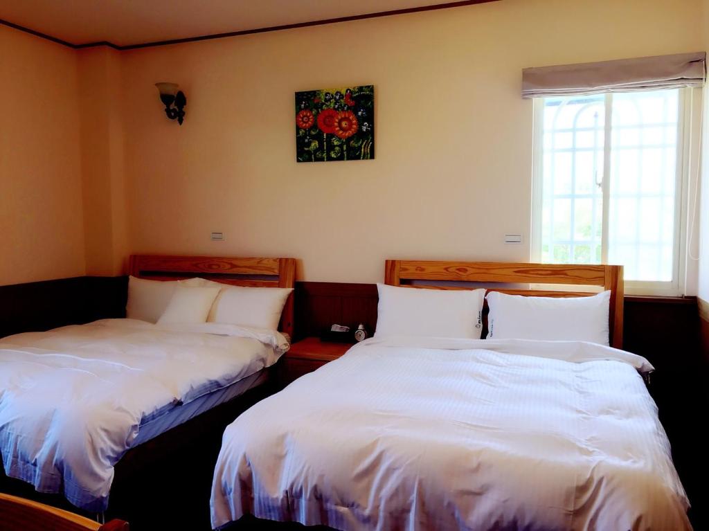 dos camas sentadas una al lado de la otra en una habitación en Onion Manor B&B歐尼恩莊園0549 en Hengchun Old Town